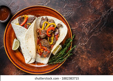 Fajitas Tortilla wraps with beef meat steak stripes, sweet pepper and onions. Dark Wooden background. Top view. Copy space
