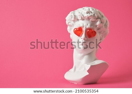Photo of fake bust of david with red glass hearts on the eyes, love concept, valentine's day congratulations