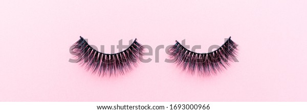 Fake eyelashes on pastel pink\
background. Beauty concept. Makeup cosmetics. Top view, flat lay.\
Layout. Place for text and design. Web Banner. Minimal\
style