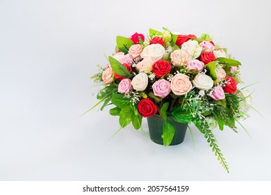 Fake flowers, bunches of roses, arranged in a vase, on a white floor.