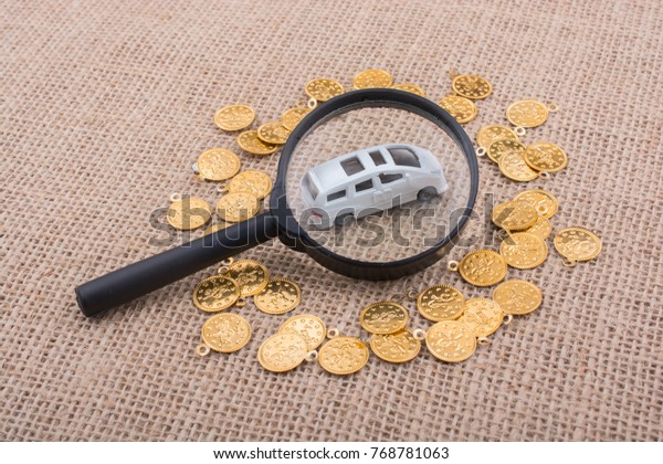 Fake gold\
coins and toy car under magnifying\
glass