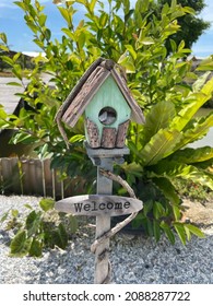 A Fake Mint Green Wooden Birdhouse Under The Sun With Welcome Wording At Below.