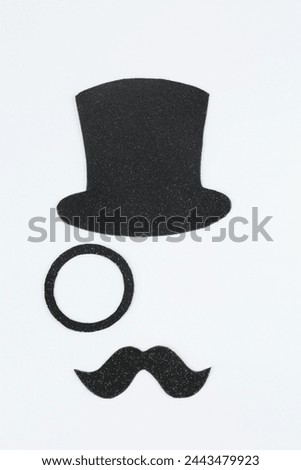 Fake mustache, hat and monocle on light background, top view