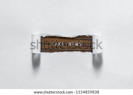 Fake News - an inscription in a torn white paper. The concept of false information, manipulation, propaganda.