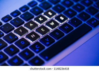Fake news written on a backlit laptop keyboard close-up with selective focus in a blue ambiant light