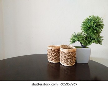 Fake Pot Plant (Fake Tree) And Wicker Basket On The Table Over White Wall.