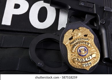 Fake prop badge designed by photographer on wood with firearm and bullets. Badge number is also fake.  Macro shot with focus on the word agent.  