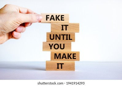Fake it until you make it symbol. Wooden blocks with words 'Fake it until you make it'. Businessman hand. Beautiful white background. Business, popular quotation concept. Copy space.