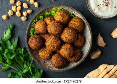 falafel balls in a ceramic bowl on a black background, top view