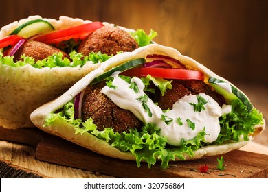 Falafel and fresh vegetables in pita bread on wooden table