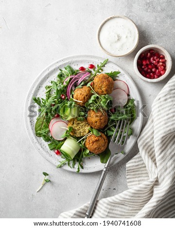 Falafel and fresh vegetables salad on a white ceramic plate on concrete background, top view.  Stock photo © 