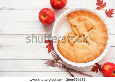Fall apple pie. Overhead view table scene with slice removed on white wood background. Copy space.