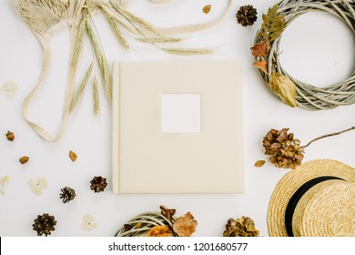 Fall Autumn Composition With Wedding Or Family Photo Album, Wreath Frame, String Bad, Rye Ears, Cones, Dry Leaves, Straw Hat On White Background. Flat Lay, Top View Still Life Mock Up Concept.