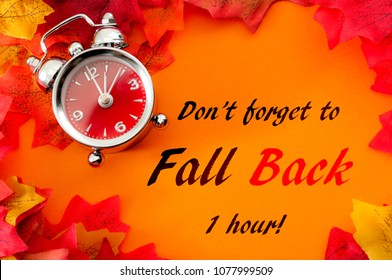 Fall Back, The End Of Daylight Savings Time And Turn Clocks Back On Hour Concept With A Clock Surrounded By Dried Yellow Leaves With The Text Don't Forget To Fall Back On Hour