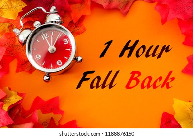 Fall Back, The End Of Daylight Savings Time And Turn Clocks Back On Hour Concept With A Clock Surrounded By Dried Yellow Leaves With The Text One Hour Fall Back