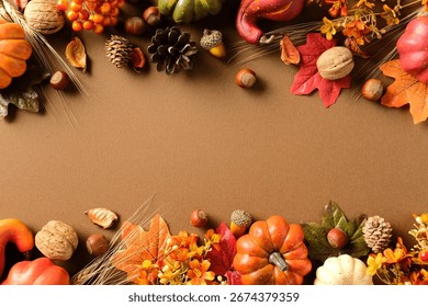 Fall border composition on brown background with pumpkins, pinecones, nuts, wheat stalks, berries and colorful leaves