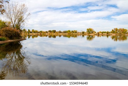 Fall Colors, Clouds and Sky Reflecting Off Calm Lake in Adams County, Colorado.