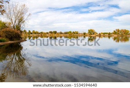 Fall Colors, Clouds and Sky Reflecting Off Calm Lake in Adams County, Colorado.