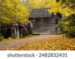 Fall colors on the trees and ground surround Mingus grist Mill in Smoky Mountains National Parka, raised water channel feeds the milll.