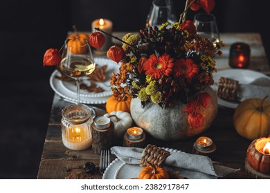 Fall composition. Orange pumpkins, flowers and candles on wooden table. Family elegant Thanksgiving or halloween dinner. Cozy autumn concept, simple handmade decoration, countryside style, wine