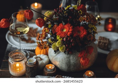 Fall composition. Orange pumpkins, flowers and candles on wooden table. Family elegant Thanksgiving or halloween dinner. Cozy autumn concept, simple handmade decoration, countryside style, wine