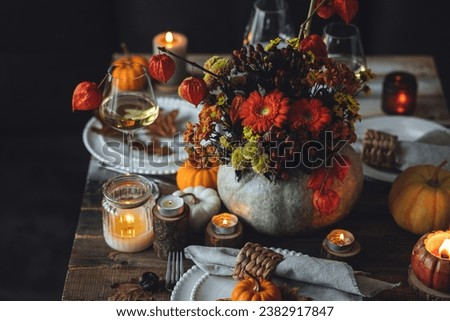 Fall composition. Orange pumpkins, flowers and candles on wooden table. Family elegant Thanksgiving or halloween dinner. Cozy autumn concept, simple handmade decoration, countryside style, wine