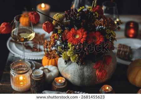 Fall composition. Orange pumpkins, flowers and candles on wooden table. Family elegant Thanksgiving or halloween dinner. Cozy autumn concept, simple handmade decoration, countryside style, wine