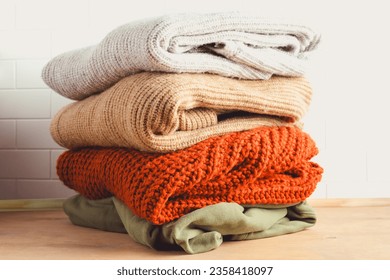 Fall composition with stack of beautifully knitted sweaters. Perfect for conveying warmth, style, and the spirit of autumn