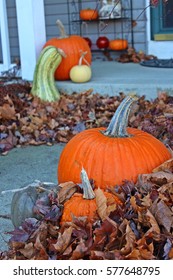 Fall decorations, various pumpkins and gourds on front walkway/porch surrounded by fall leaves