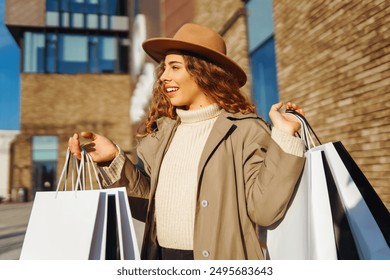 Fall elegant woman carrying shopping bags walking city street. Consumerism, sale, purchases, shopping, lifestyle concept. - Powered by Shutterstock