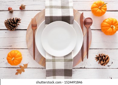 Fall Harvest Or Thanksgiving Dinner Table Setting With Plate, Flatware, Check Print Napkin, Pumpkins And Decor. Above View On A White Wood Background.