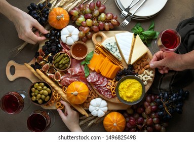 Fall Holidays Party Table With Friends Hands Picking Some Fingerfoods From Charcuterie Board, Top Down View