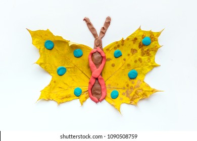 Fall Leaf Crafts for Kids. Craft handmade butterfly from dry yellow leaves and red, brown and blue plasticine, modeling clay. Ideas for kids arts and crafts isolated on white - Powered by Shutterstock