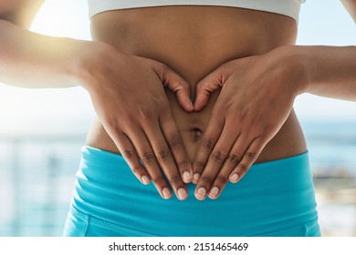 Fall in love with taking care of yourself. Cropped shot of a healthy woman forming a heart shape over her stomach. - Shutterstock ID 2151465469