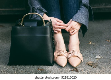 fall outfit fashion details, young stylish woman wearing oversized grey sweater, jeans and beige loafers. urban fashion blogger posing with a black trendy handbag.
