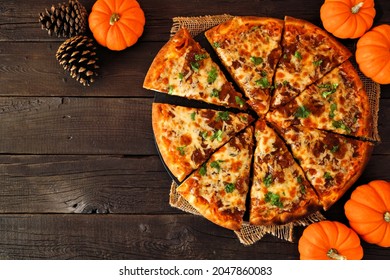 Fall pizza with pumpkin sauce, gouda and caramelized onions. Above view on a dark wood background. Copy space.