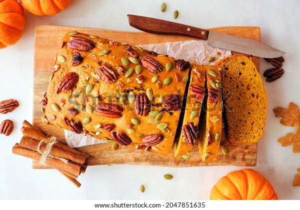 Fall pumpkin bread sliced. Overhead view\
table scene on a white marble\
background.