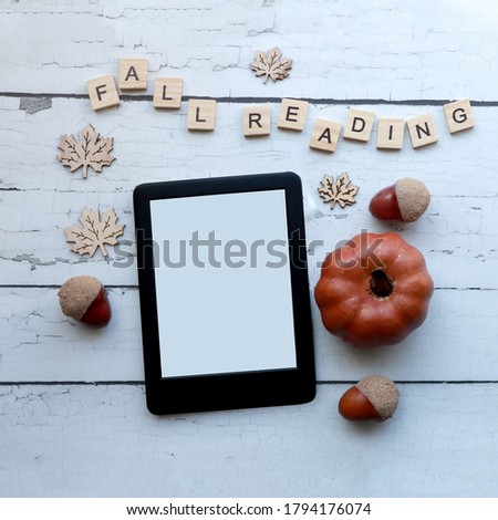                      Fall reading:  top view of an emptyebook on a rustic white wood surface surrounded by fall themed items and wooden letter tiles .
autumn themed ereader flat lay with copy space   