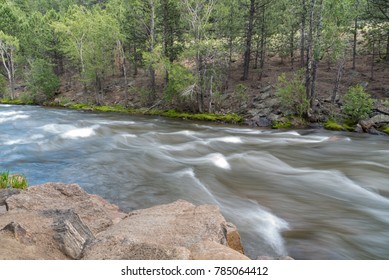 Fall River Flowing In Estes Park, Colorado On A Summer Day. The Motion Is Captured Of The River With Trees Lining The Bank.