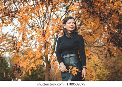 Fall Scene Beautiful Autumn Portrait Of Attractive Young Woman In Park Against Tree With Yellow Orange Leaves Holding A Tender Twig And Looking Away In The Distance