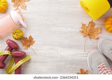 Fall season strength training. Top view photo of trendy sneakers, tape measure, dumbbells, plastic bottle, karemat, pumpkin, fallen leaves on light wooden background with ad zone - Shutterstock ID 2366534311