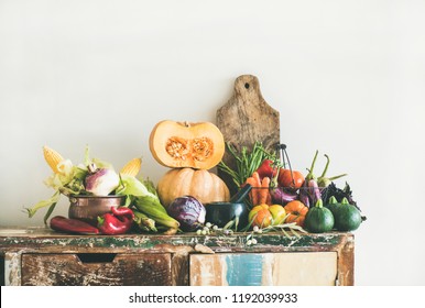 Fall Seasonal Vegetarian Food Ingredients Variety. Assortment Of Autumn Vegetables For Healthy Cooking Over Rustic Kitchen Cupboard, White Wall Background, Copy Space. Local Market Organic Produce