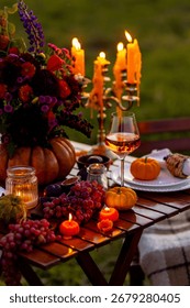Fall table decoration with pumpkins, wine, candles. Family cozy thanksgiving dinner arrangement outdoors, wedding elegant decor. Countryside style, simple handmade setting, autumn mood, inspiration