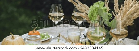 Fall table decoration with pumpkins, wine. Family thanksgiving dinner arrangement outdoors in the garden. Countryside style, simple handmade setting, autumn mood banner