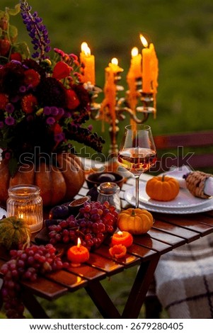 Fall table decoration with pumpkins, wine, candles. Family cozy thanksgiving dinner arrangement outdoors, wedding elegant decor. Countryside style, simple handmade setting, autumn mood, inspiration