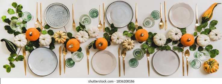 Herbsttisch zum Feiern Thanksgiving- oder Friendsgiving-Tag, Familienfeier oder Versammlungen. Platten, Besteck, Glaswaren, bunte Kürbisse und Blätter auf weißem Hintergrund, Draufsicht
