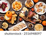 Fall theme appetizer table scene against a dark wood background. Charcuterie board, pumpkin and apple dips, crostini, cheeses and snacks. Top down view.