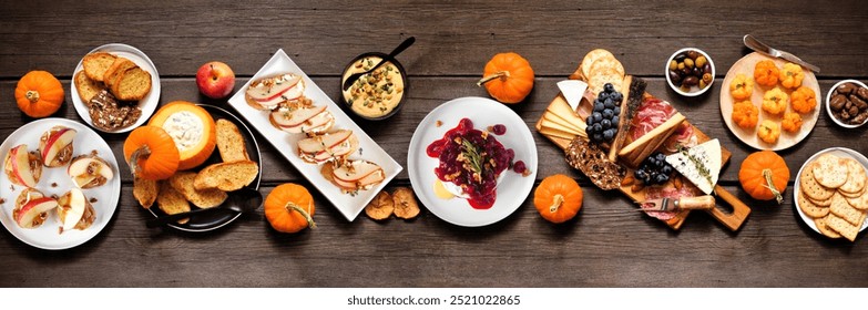 Fall theme appetizer table scene against a dark wood banner background. Charcuterie board, pumpkin and apple dips, crostini, cheeses and snacks. Above view. - Powered by Shutterstock