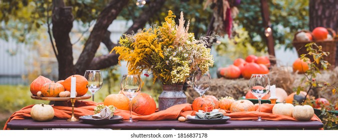 Fall Themed Holiday Table Setting Arrangement For A Seasonal Party, Glasses, Pumpkins, Candles, Field Flowers