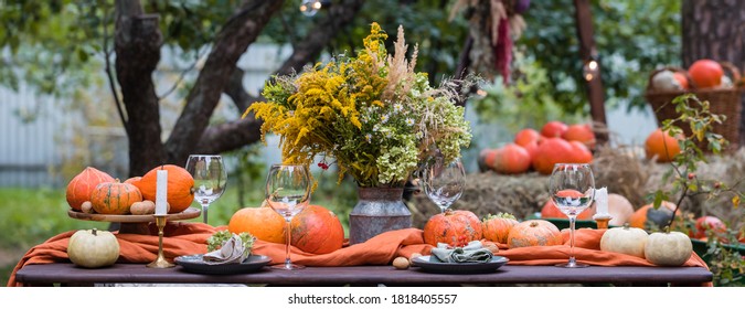 Fall Themed Holiday Table Setting Arrangement For A Seasonal Party, Glasses, Pumpkins, Candles, Field Flowers